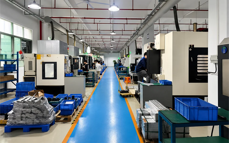 CNC workshop with machining equipment and production activity along a central aisle