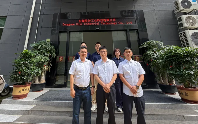 OUJI team at the company entrance, with the Dongguan Ouji Industrial Technology name displayed above the door