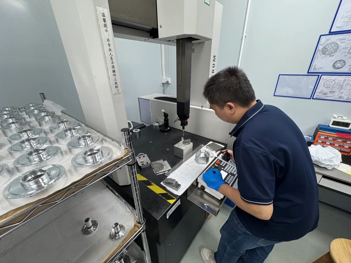 An OUJI technician operating a CMM beside a trolley of machined parts