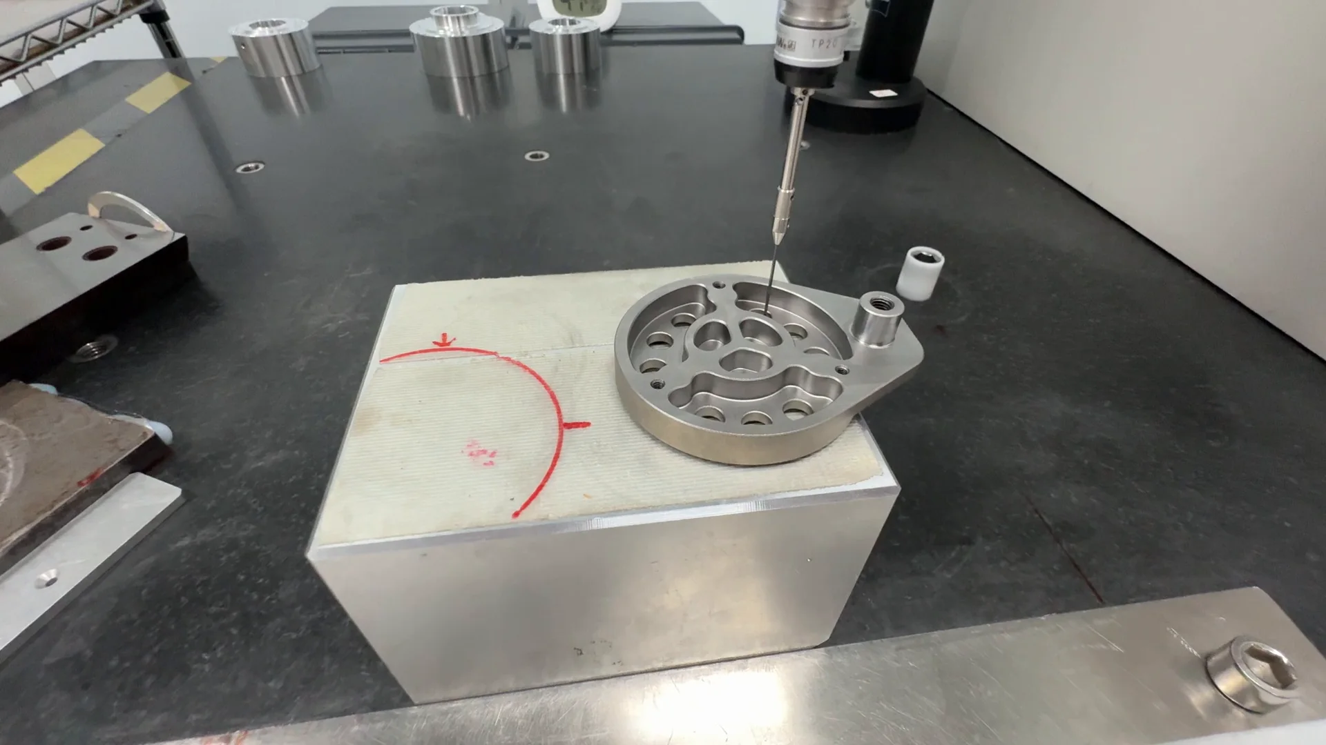 CMM probe inspecting a machined component on the measurement table at OUJI