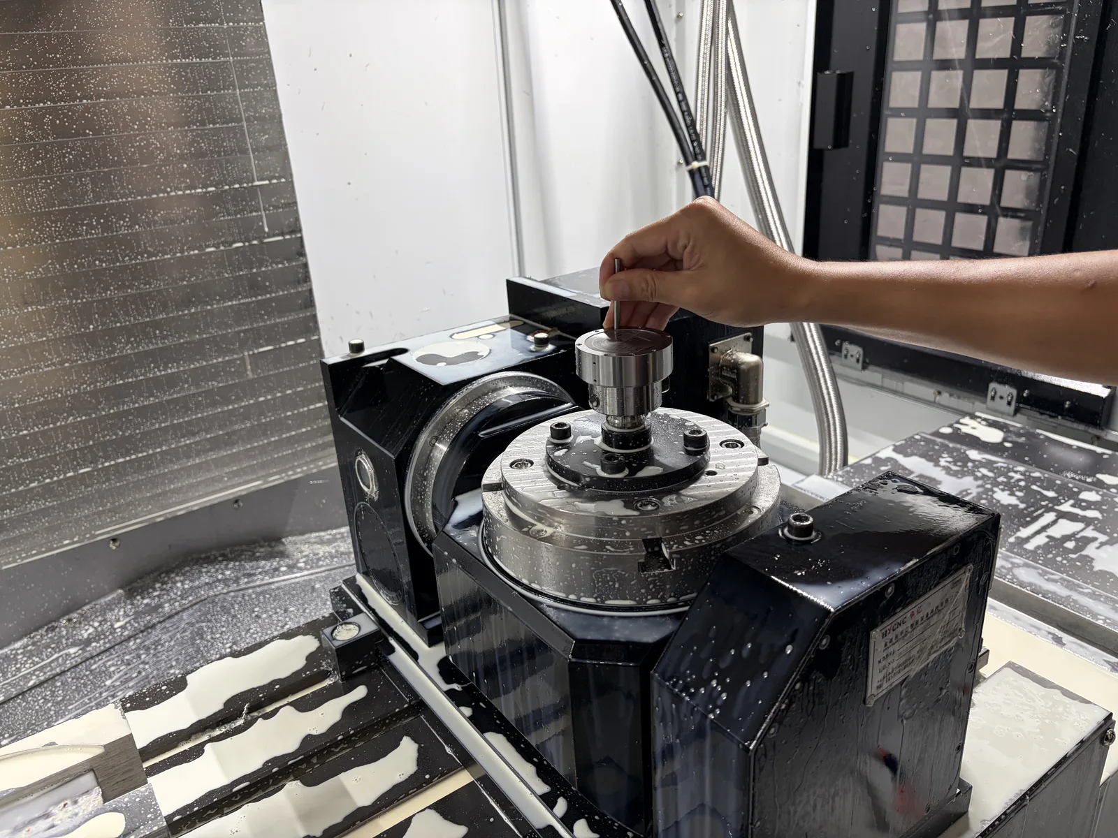 Machinist indexing a rotary fixture on a CNC machining center between operations