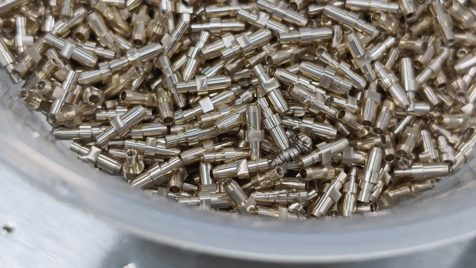 Close-up of micro-turned brass connector contacts showing stepped diameters, knurling and through-bores