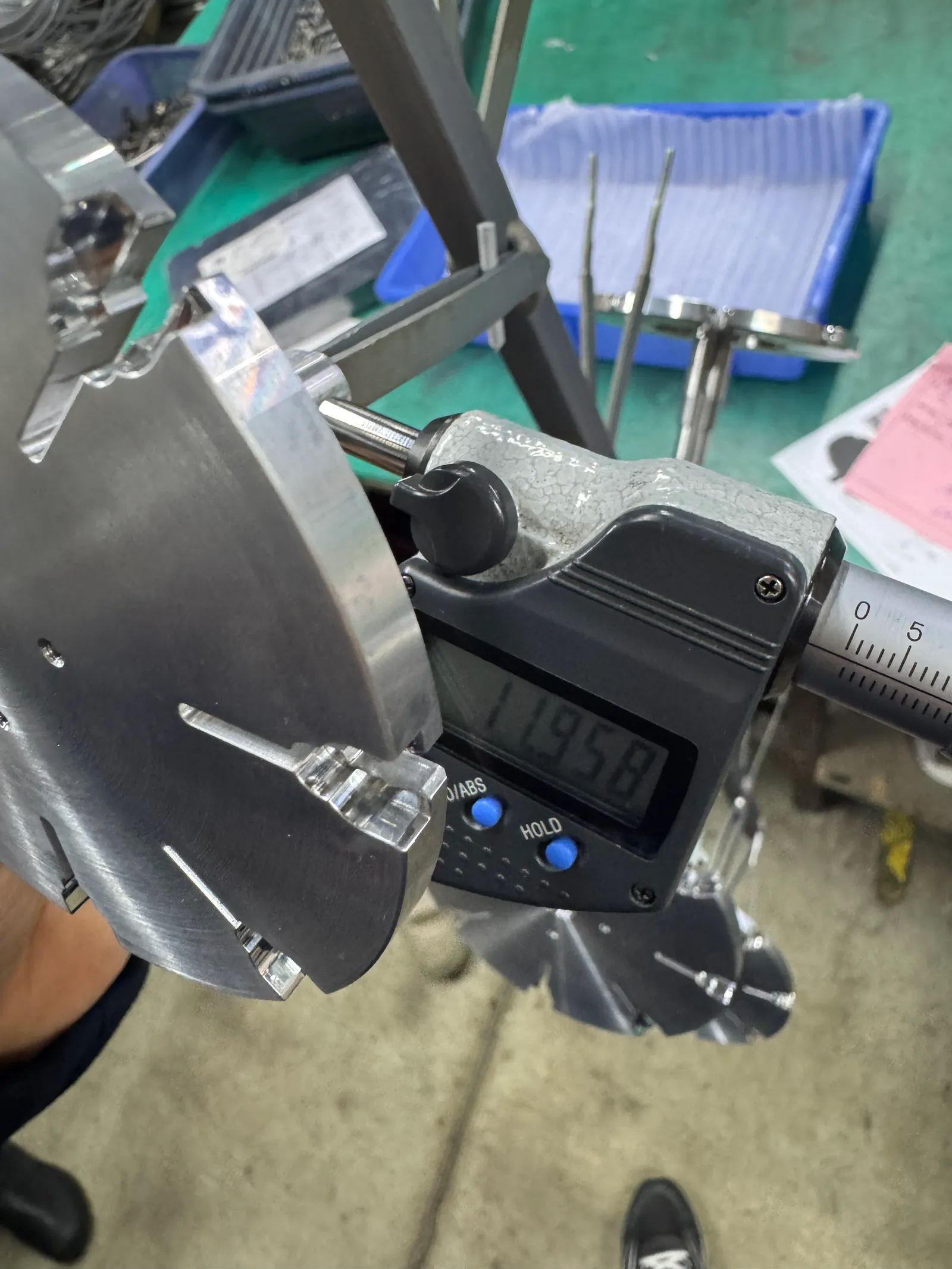 Digital caliper measuring a critical dimension on a machined part during finishing verification