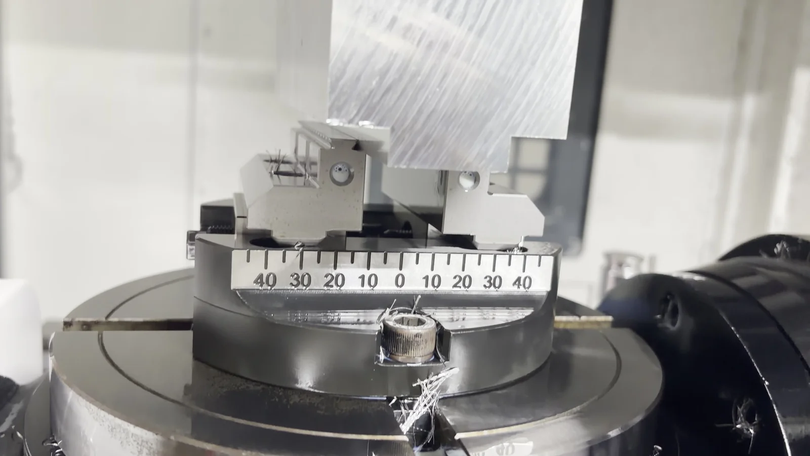 Close view of an aluminum blank held by a dovetail fixture on a CNC rotary table