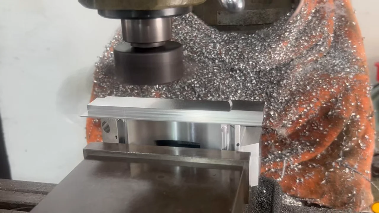 Conventional vertical milling operation removing the temporary clamping portion from the aluminum part