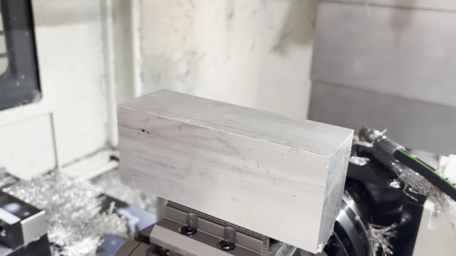 Rectangular EN AW-6082 aluminum blank positioned on a rotary table inside a CNC machining center