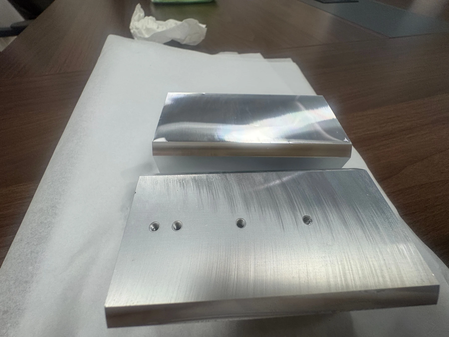 Two 5083 aluminum optical-equipment components showing machined faces, threaded holes and reflected light