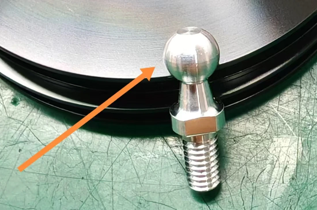 Rejected aluminum ball-head screw with the original orange arrow indicating the surface defect area