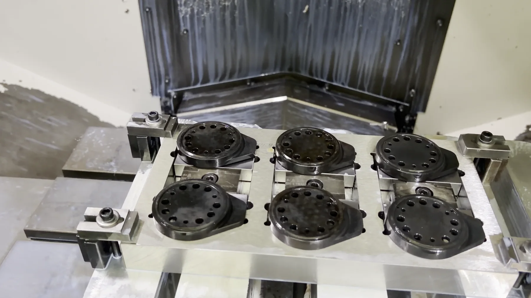 Six anonymized AerMet 100 components clamped in the revised finish-milling fixture