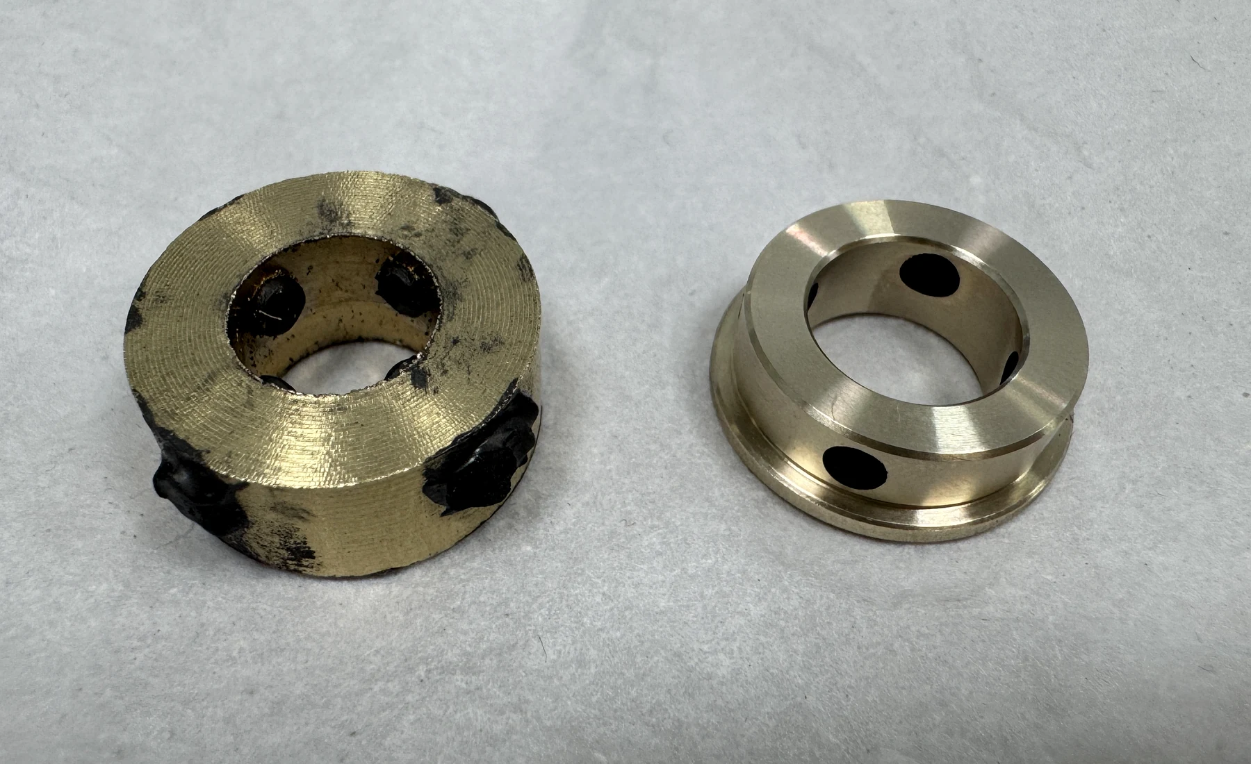 Side-by-side graphite-insert brass bushings before and after final precision turning