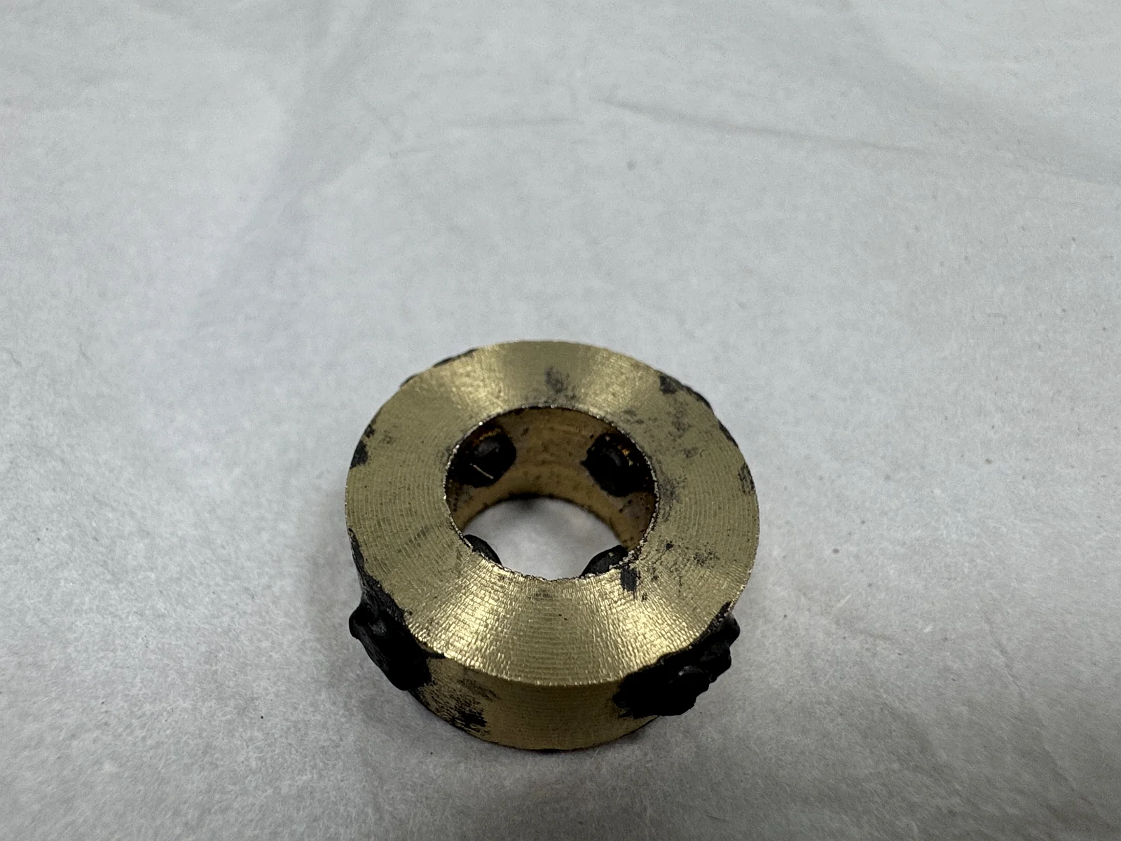 High-strength brass bushing after graphite filling and before final precision turning, with black graphite standing proud of the surfaces