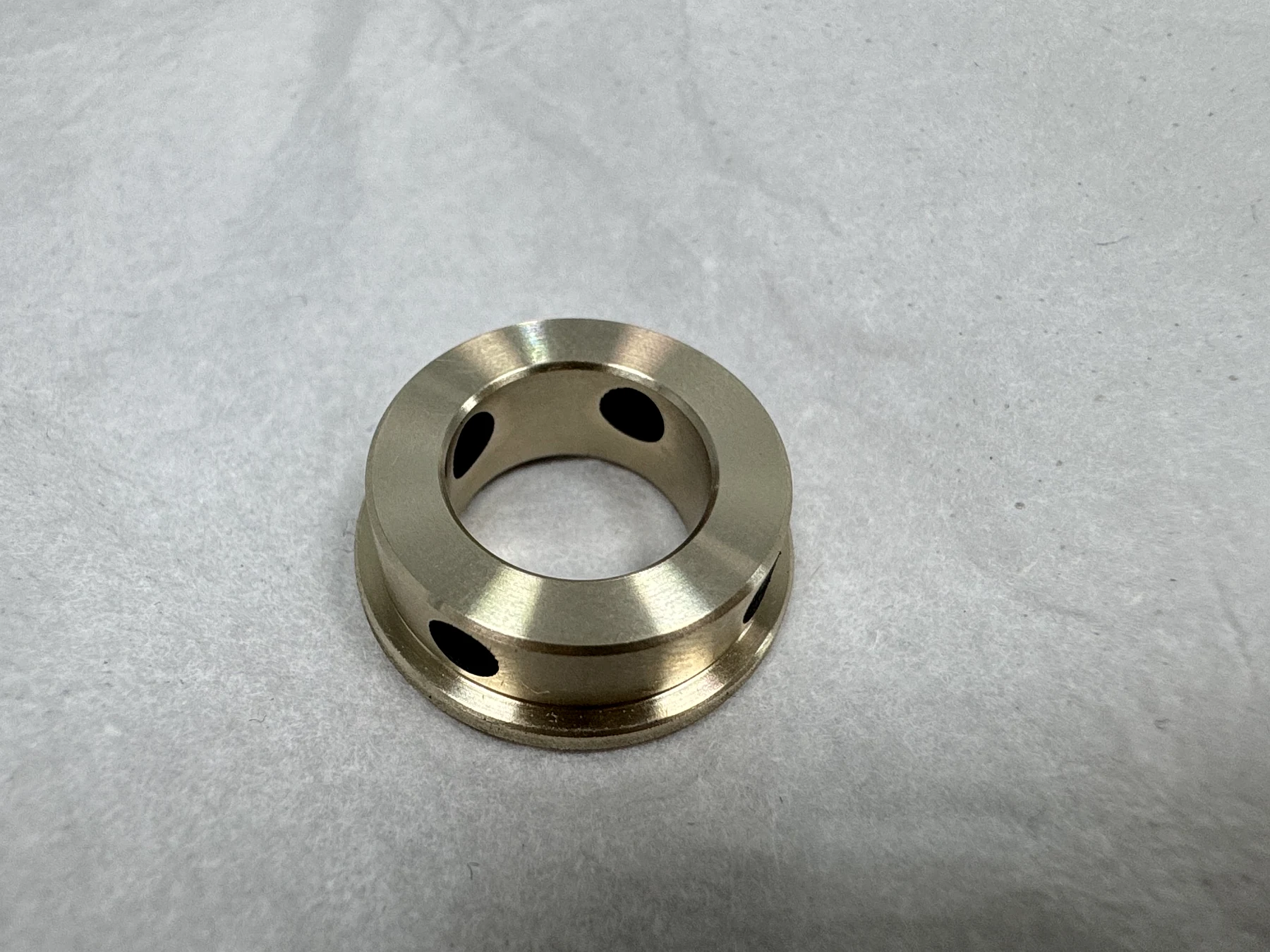 Finished high-strength brass robot joint bushing with black graphite lubrication inserts machined flush with the bearing surfaces