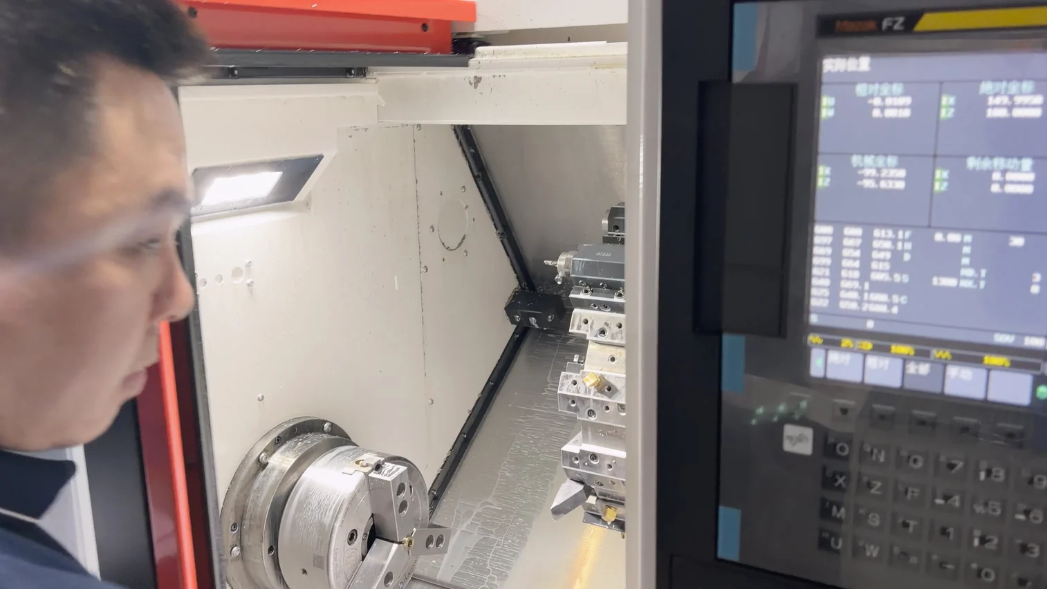 Operator reviewing a small brass bushing held in an OUJI Mazak CNC turning cell