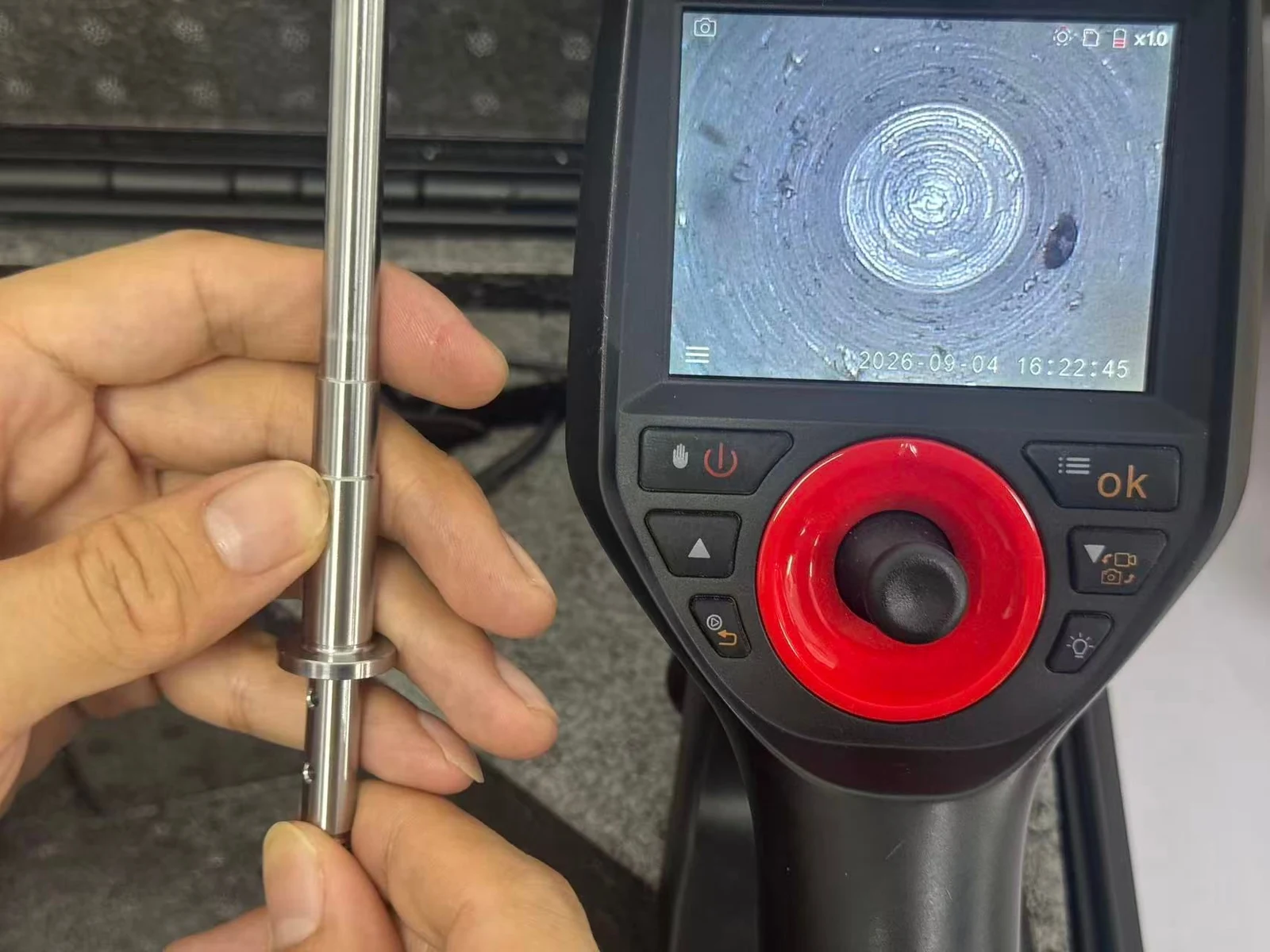 Industrial borescope inspecting the internal bore of a SUS431 part, with the bore view visible on its screen