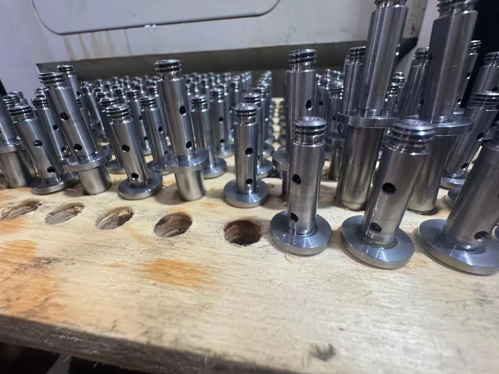 SUS431 machined parts with external threads and radial holes arranged upright on a production tray