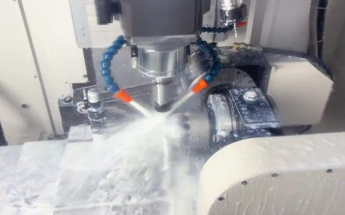 CNC milling spindle and workpiece under coolant inside the machining enclosure
