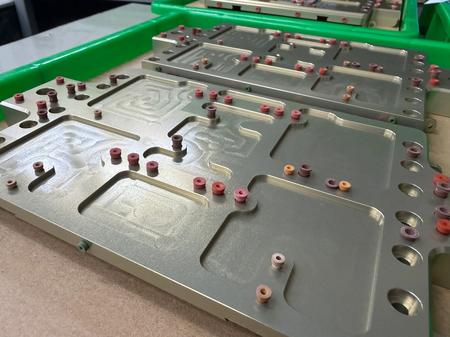 Machined housings with masking plugs protecting selected holes and surfaces for partner-applied finishing