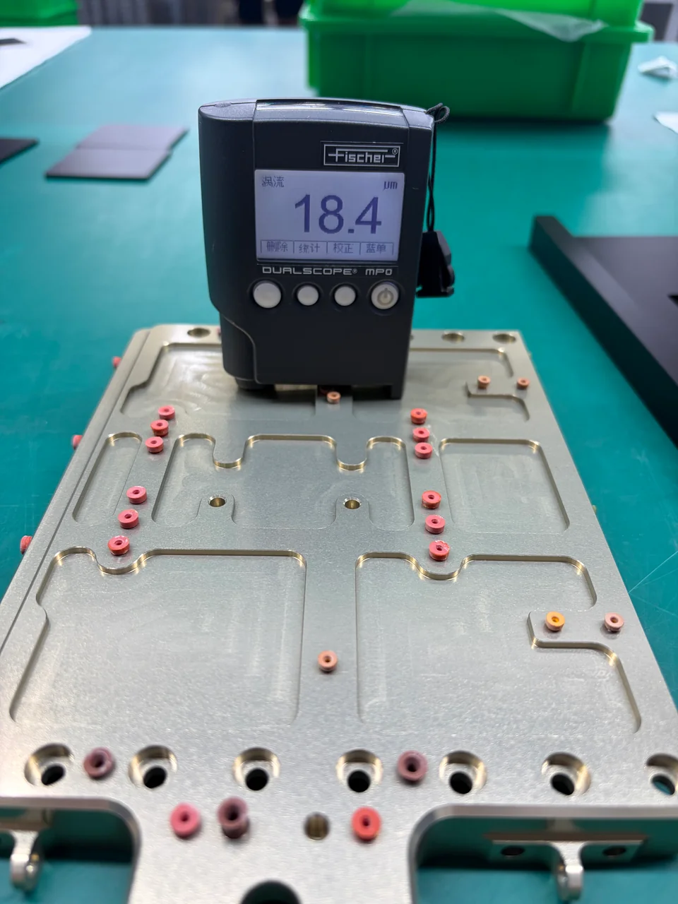Coating-thickness gauge taking a spot measurement on a masked machined part at a finishing partner
