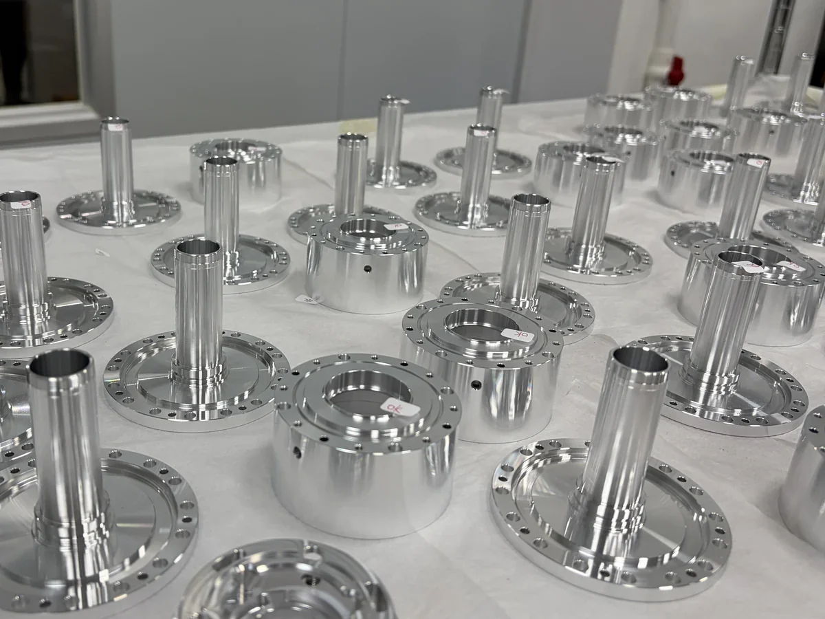 Rows of OUJI machined metal components for robotic equipment, with turned shafts, flanges and mounting holes