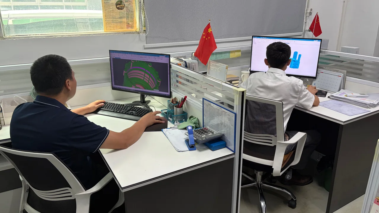 OUJI engineering team reviewing part models at CAD workstations