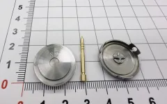Small OUJI machined parts on a graduated measuring board