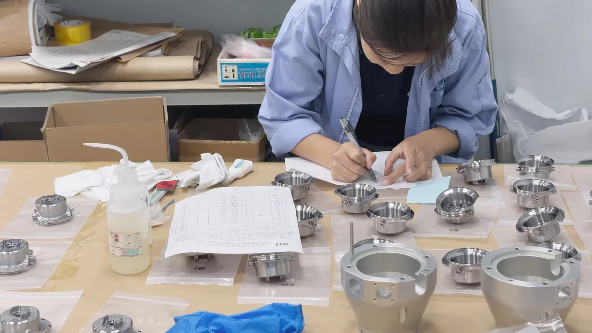 OUJI team member recording part information beside machined components arranged on individual packaging bags